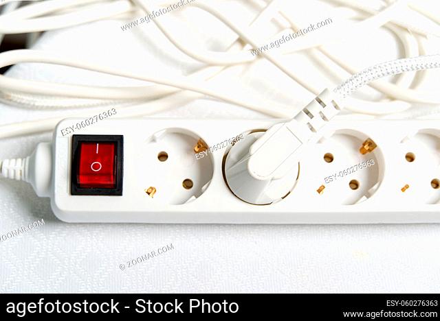european household white extension cord for 220v with fuse on white textile. close-up
