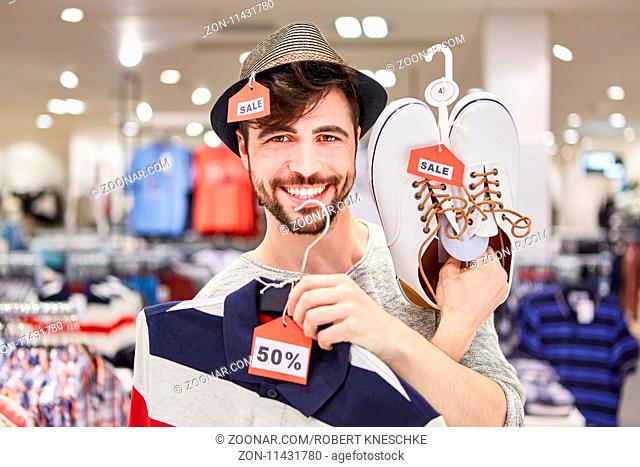 Glücklicher junger Mann findet Sonderangebote beim Shopping im Einzelhandel