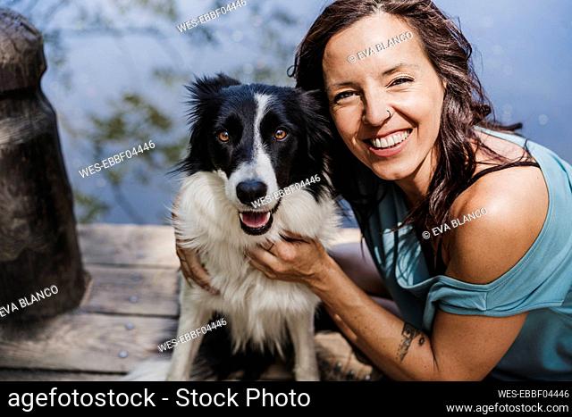 Happy woman with Border Collie sitting on pier