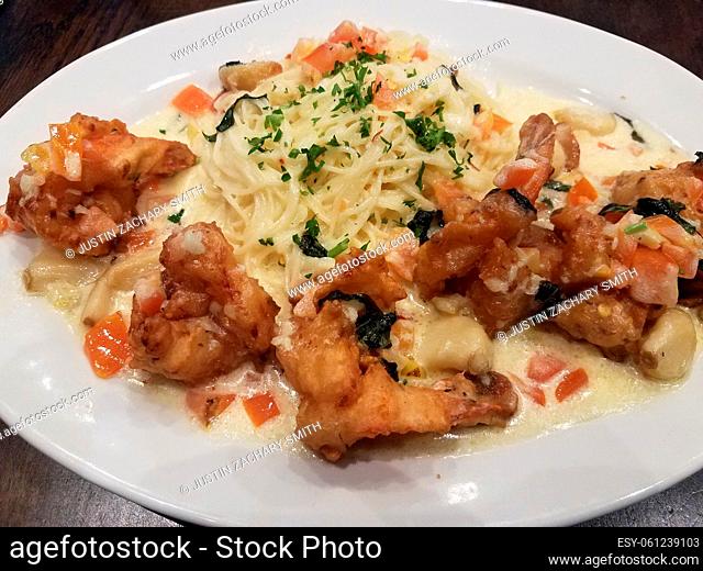 italian pasta with fried shrimp and sauce on a plate with garlic and tomato