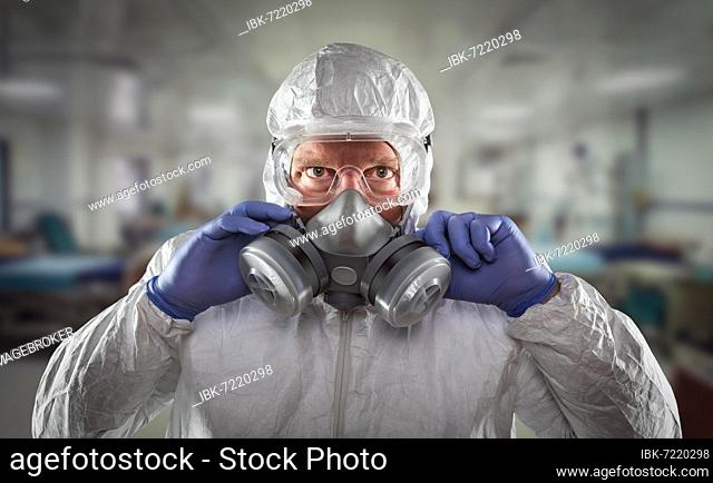 Man wearing hazmat suit, protective gas mask and goggles reaching to stop with hands within hospital