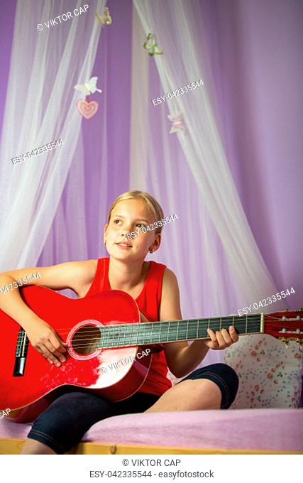 Teenage girl with her guitar in her lovely room