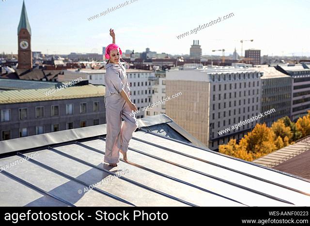 Carefree woman with headphones dancing at rooftop