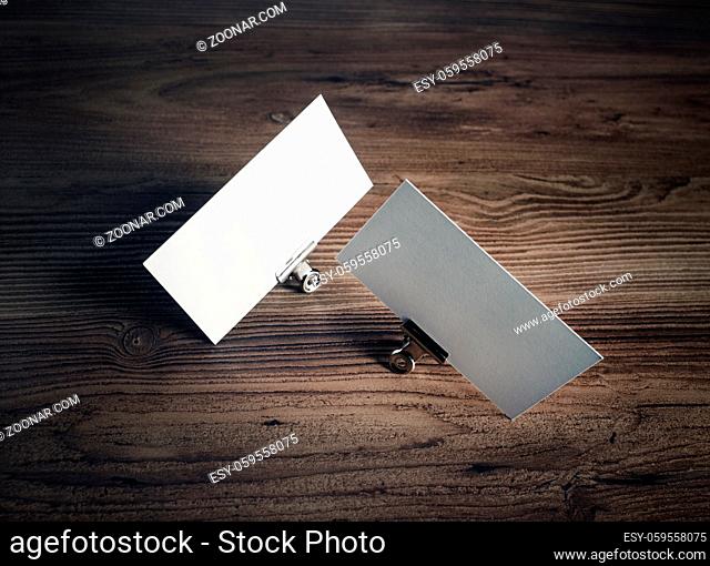 Photo of blank business cards and metal binder clips on wooden background