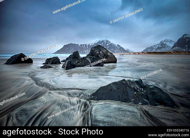 Rocks on Norwegian sea beach in fjord. Skagsanden beach, Flakstad, Lofoten islands, Norway. Long exposure motion blur