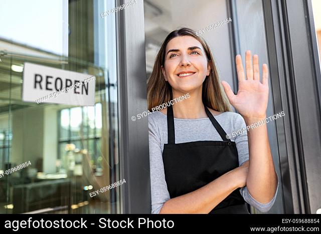 happy woman with reopen banner to door glass