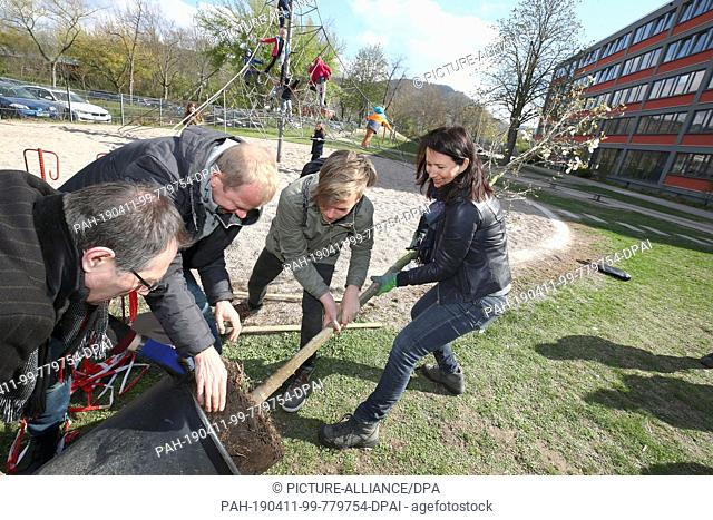 11 April 2019, Thuringia, Jena: Anja Siegesmund (M, Bündnis90/Die Grünen), Environment Minister of Thuringia, is planting a magnolia tree together with teachers...