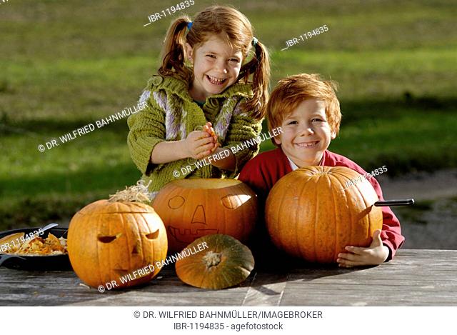 Two children carving pumpkins for Halloween decoration