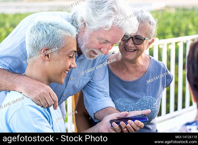 grandparents with grandson having a looking at mobile phone. happy multi generation family looking at the back of a mobile phone device
