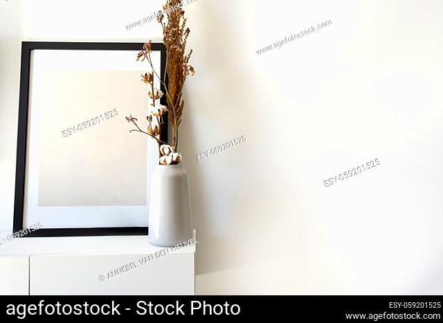 Empty wooden photo, picture frame mock-up with white vase and stylish plant near white wall on table, Copy space modern decoration interior space for text