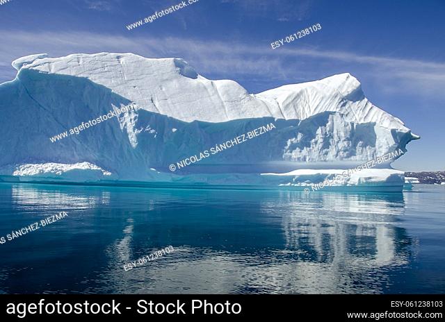 Iceberg floating in a blue and calm sea in a sunny day