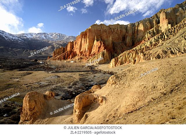 The village of Dhakmar and red cliff with caves at sunset. Nepal, Gandaki, Upper Mustang (near the border with Tibet)