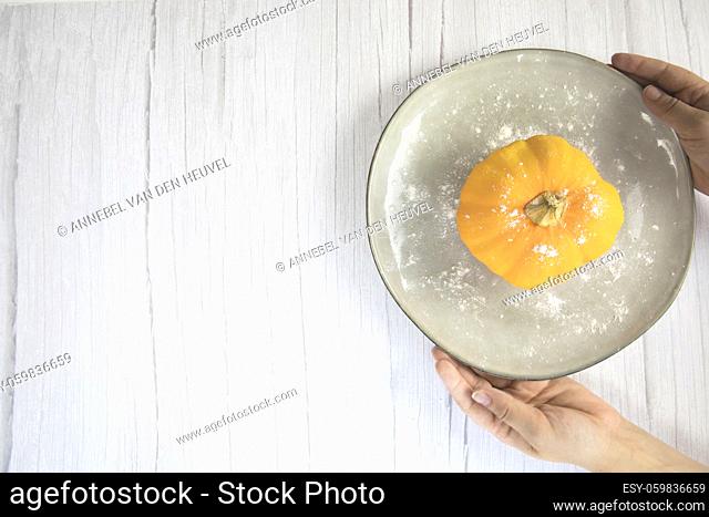 Orange pumpkin on white wooden background with copy space on natural plate top view, autumn harvest, Halloween or Thanksgiving concept space for text