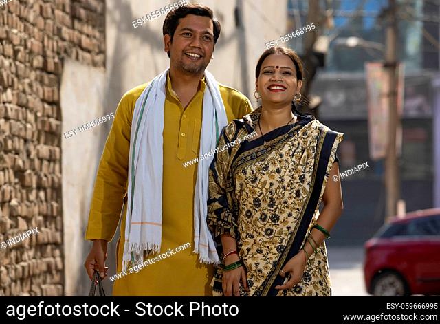 A HUSBAND AND WIFE HAPPILY STANDING TOGETHER ON A STREET