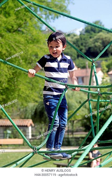 Child playing on a spiderweb, France
