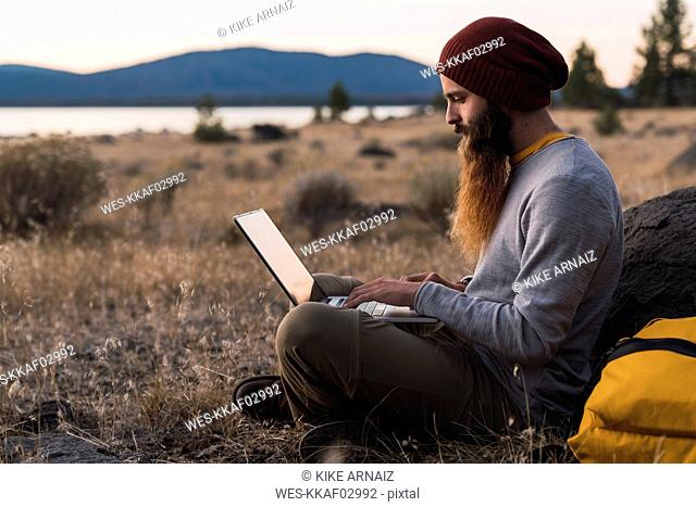 USA, North California, bearded young man using laptop near Lassen Volcanic National Park