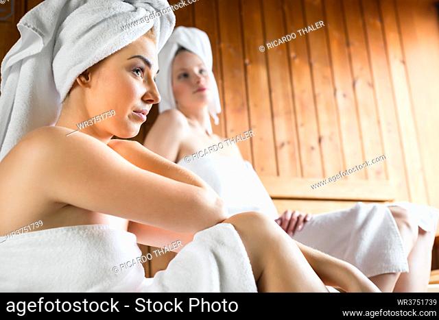 Two Women in wellness spa relaxing in wooden sauna