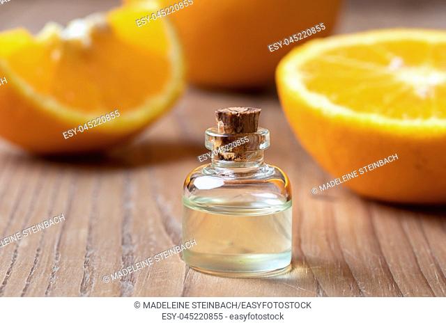 A bottle of citrus essential oil with fresh oranges in the background