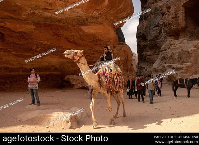 19 October 2018, Jordan, Petra: A Bedouin boy rides a camel in the historic rock town of Petra. According to Jordanian information