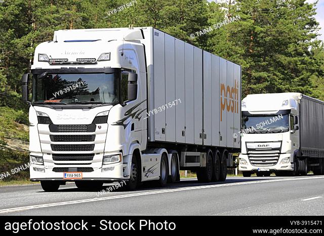 White Scania S500 and DAF XF semi trailer trucks transport goods on Highway 3 Southbound in the summer. Ikaalinen, Finland. August 12, 2021