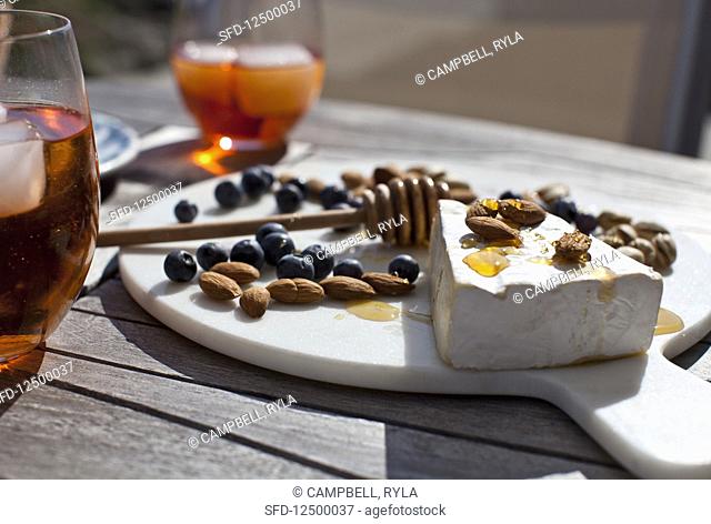 Cheeseboard with brie drizzled with honey, blueberries, almonds and pistachios