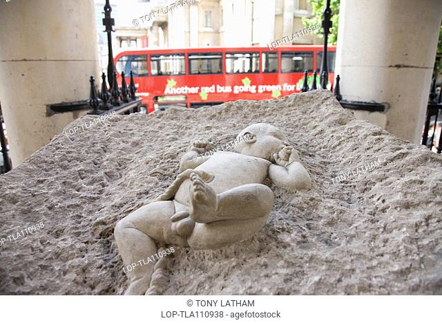A sculpture of a new born baby in a block of concrete outside St Martin in the Fields near Trafalgar Square. The sculpture is by Mike Chapman and was originally...