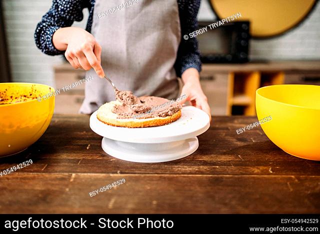 Female person hands smears cake with chocolate cream. Tasty dessert homemade cooking