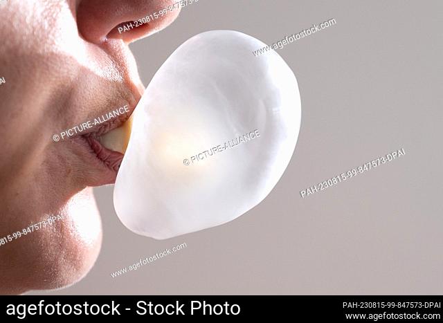 ILLUSTRATION - 15 August 2023, Saxony, Dresden: A woman forms a bubble gum bubble with her mouth. Photo: Sebastian Kahnert/dpa