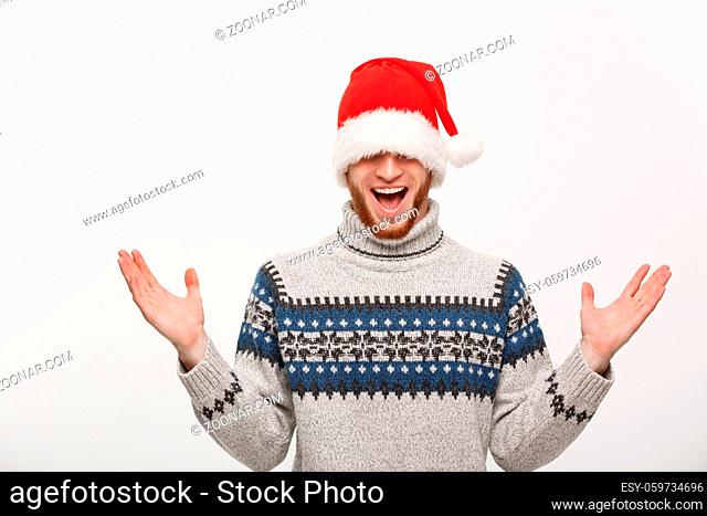 Holiday Concept - Young beard man in sweater enjoy playing with santa hat