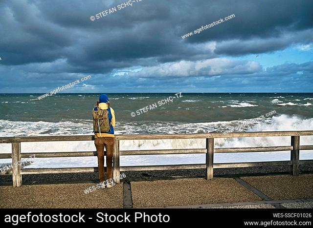 Tourist admiring sea standing on footpath at vacation