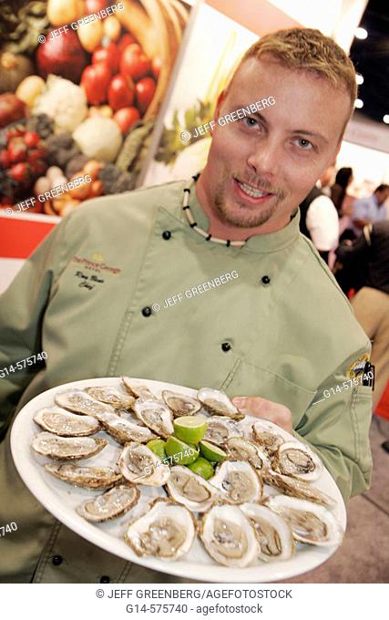 Americas Food and Beverage Show, male chef, oysters, hor d'oeuvres, plate. Convention Center. Miami Beach. Florida. USA