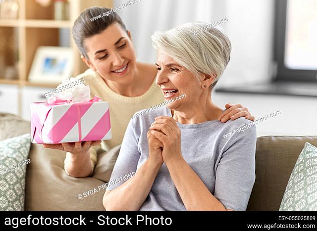 adult daughter giving present to her senior mother
