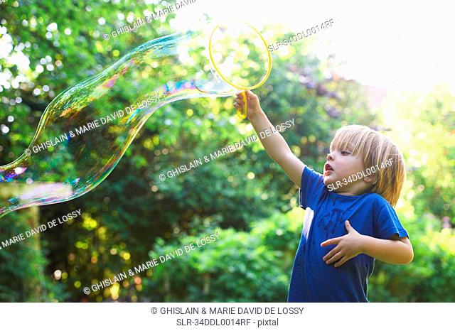 Boy making oversized bubble in backyard