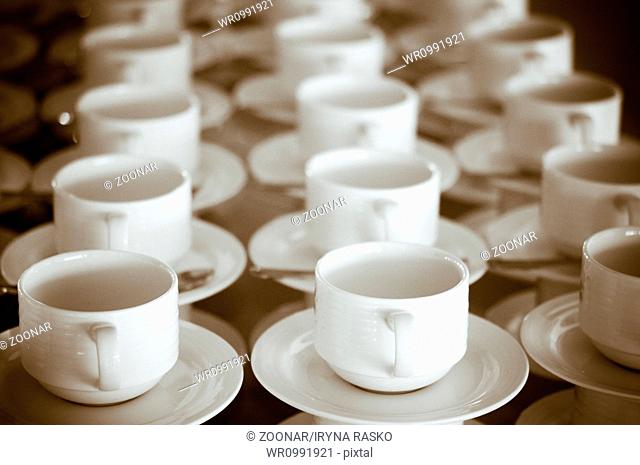 Many rows of white cups and saucers in retro style