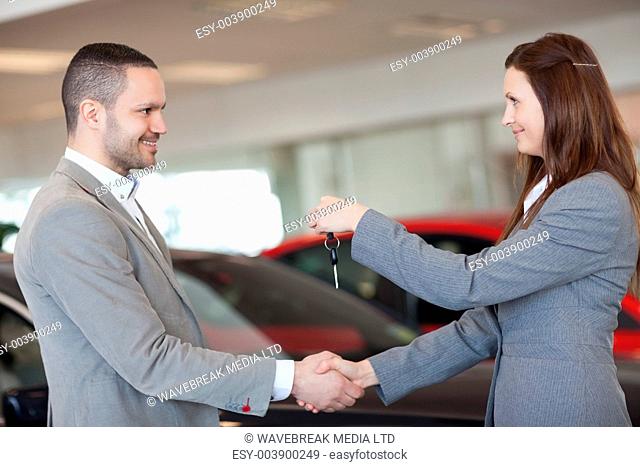 Man receiving car keys while shaking hand in a dealership