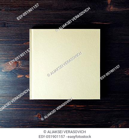 Photo of blank hardcover brochure on dark wood table background. Copy space for text. Flat lay