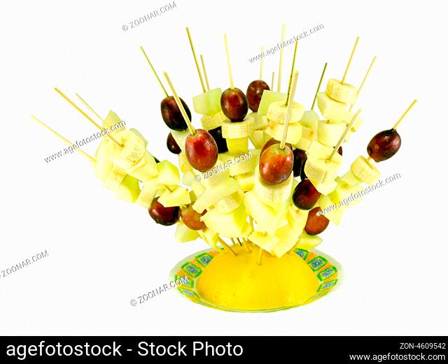 fruit grape and banana piece scewers on wooden broachs inserted in melon in small dish. healthy diet food decoration isolated on white background