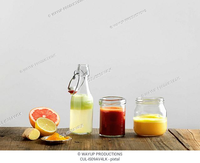 Fruit smoothies in glass bottle and jars, white background