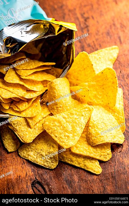 Salted tortilla chips. Yellow nachos triangle on wooden table