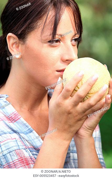 Young woman smelling a melon
