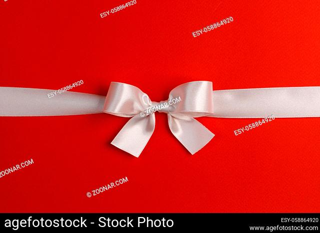 White gift bow on red background copy space for text
