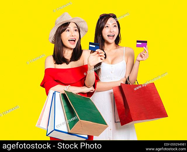 happy young women dressed in summer clothes holding shopping bags and credit cards