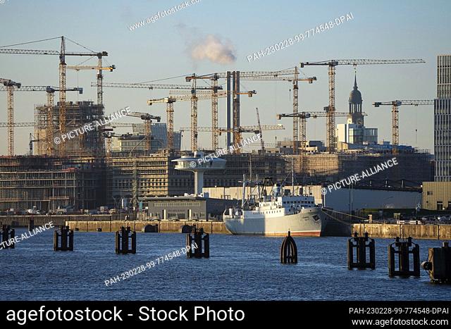 06 February 2023, Hamburg: The church of St. Michaelis (Michel) can be seen between the cranes on the Hafencity construction site