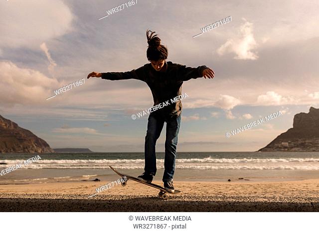 Man skateboarding on wall at beach