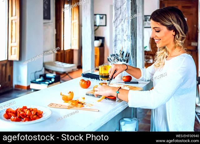 Beautiful young woman smiling and chopping vegetables for dinner