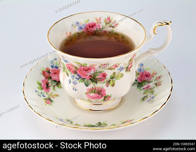 Full antique teacup and saucer with rose and gold decoration isolated on white