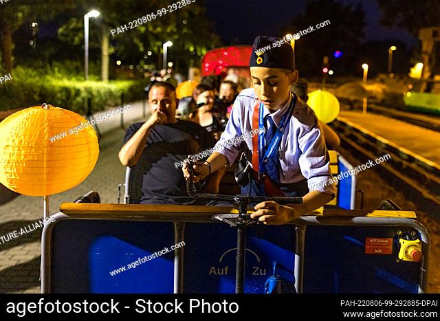 05 August 2022, Brandenburg, Cottbus: A youthful train attendant operates a coupler during the so-called light rides of the Cottbus park railroad