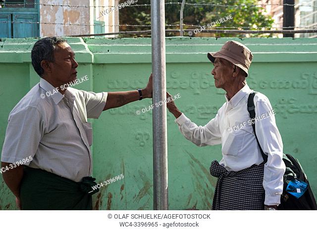 Yangon, Myanmar, Asia - Two men wait at a bus stop in the centre of the former capital and study the timetables of the city busses
