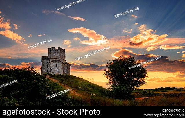 Medieval stone church of St. Nicholas Sveti Nikola near Nin, Dalmatia, Croatia, small chapel on top of hill in dramatic sunset