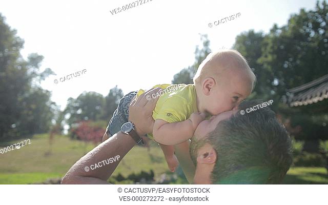 Affectionate young father lifting cute baby boy up